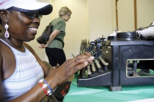 Claudette Green-Thompson, of Greenbelt, tries out the old typewritters at the Open House on Sunday. Green-Thompson said she was facinated by the "relics". Susan Smith examines the 1923 Underwood.   Jill Connor - Greenbelt News Review