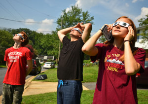 Nick Serra, Joe Natoli, and Lizzie Serra watch the solar eclipes from Lakeside Drive on Monday August 21, 2017.  Photo by Sharon Natoli