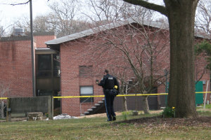 Area of suspicious bag marked off with yellow police tape, awaiting arrival of bomb squad to investigate duffle-type bag wdged between two air conditioning compressors behind the lattice screen (center of photo).