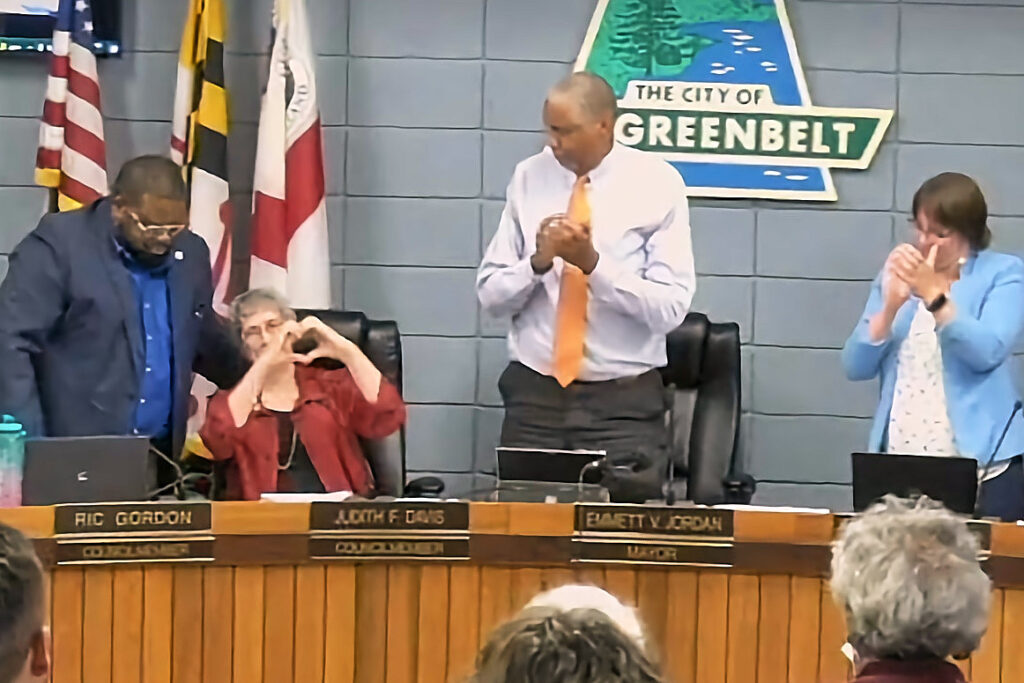 Judith Davis, seated, makes a heart shape with her hands, while Ric Gordon and Emmett Jordan stand on either side of her.