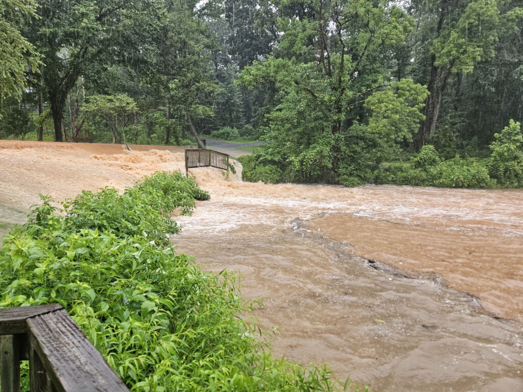 Flood water surges over lake path