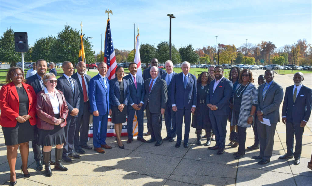 People in business clothes stand in a semi-circle on pavement.