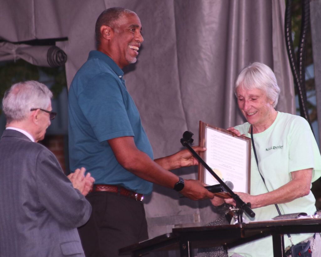 Cathie Meetre, wearing a green T-shirt with the News Review logo, accepts a plaque from Mayor Emmett Jordan.