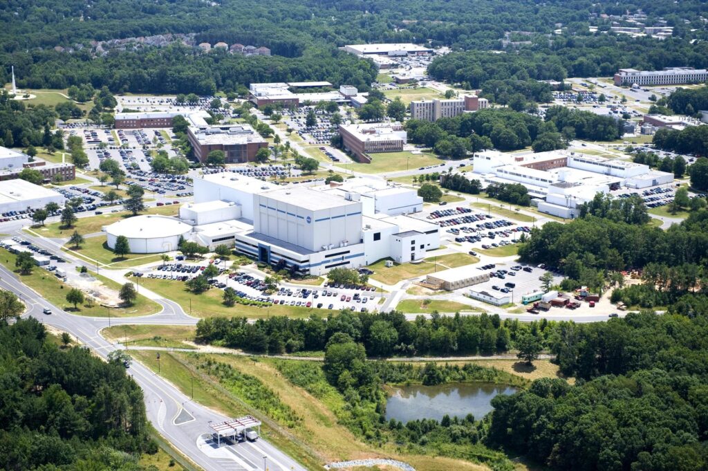 An aerial view of the NASA campus: white buildings and parking lots, scattered against green areas and trees.