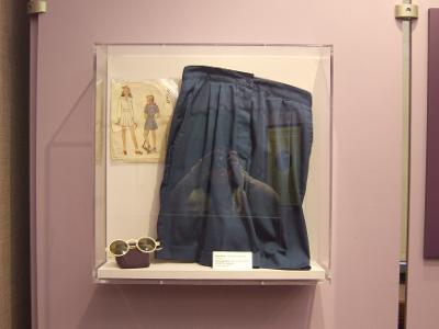 Dark-colored shorts in a glass case, with a pair of spectacles and a drawing of two women (which appears to be a sewing pattern).