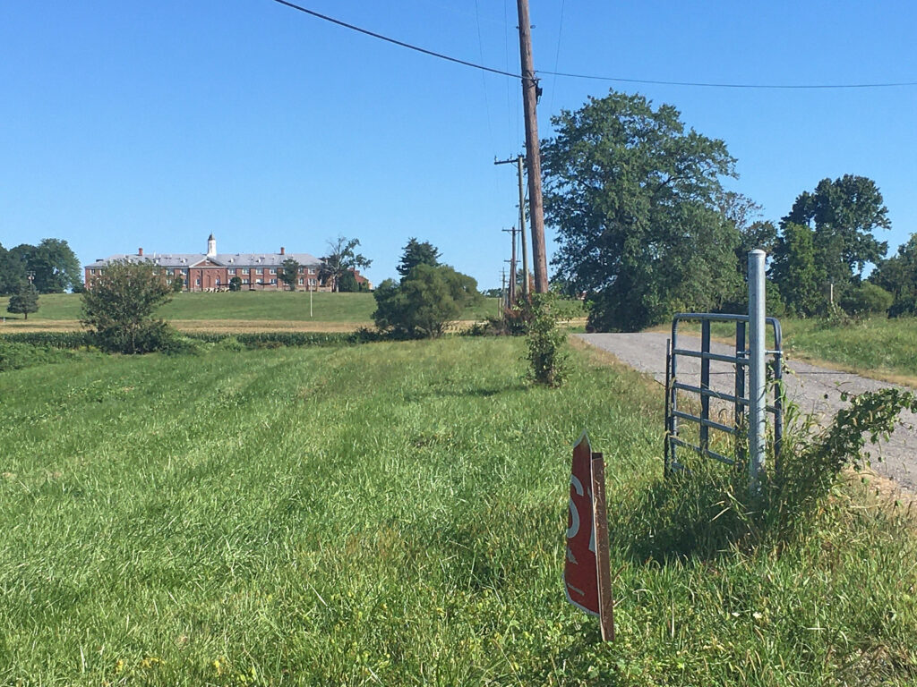 A green field with a brown building visible far in the distance.